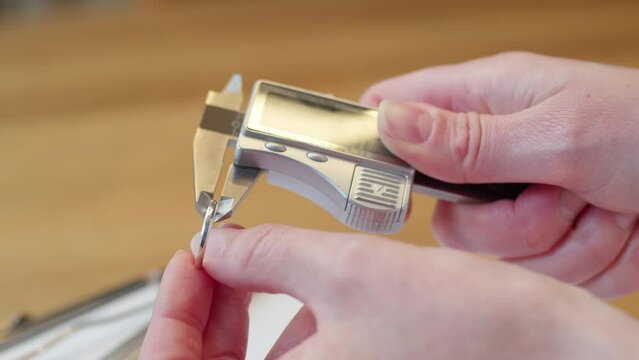 Wedding ring getting measured by woman's hand and writing on clipboard and paper with pen