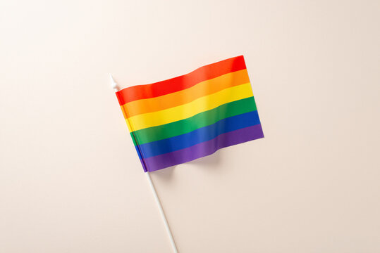 Top view photo of one rainbow LGBT pride flag with six colors on beige background