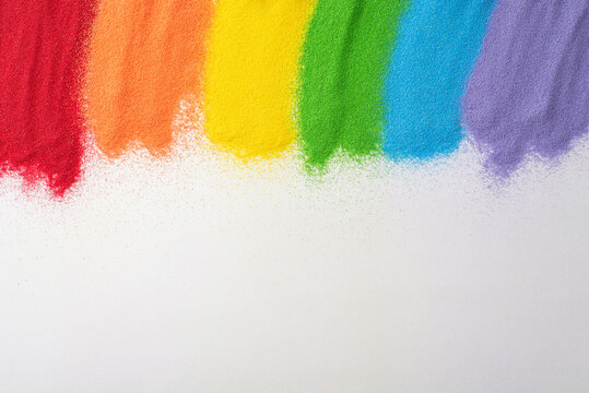 Celebrate LGBT history month with sand flag art. Top view showcases a rainbow flag made from sand on white, inviting an copy space for supportive text