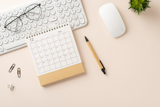 Office Environment: Overhead shot of keyboard, mouse, pen, plant-filled flowerpot, glasses, clips, and calendar on a light backdrop. Ample room for text or ads