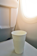 Air Travel Concepts. One Plastic Cup on Table in Plane During Flight As Idea of Alcohol Consumption on Board