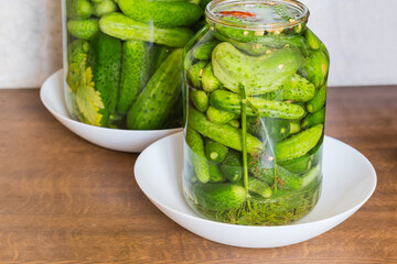 Quick pickled cucumbers in jar against other jar on table