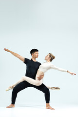 Ballet Concepts. Asian Young Man and Caucasian Woman Performing As Ballet Dancers Over Grey Studio Background Doing Suppots As Classical Dance Aesthetics