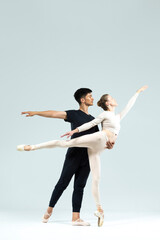 Ballet Concepts. Asian Young Man and Caucasian Woman Performing As Ballet Dancers Over Grey Studio Background Doing Suppots As Classical Dance Aesthetics With Choreography © danmorgan12