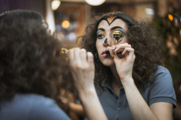 Hair and makeup preparations for the Halloween party, woman putting on her eyelashes with a tool