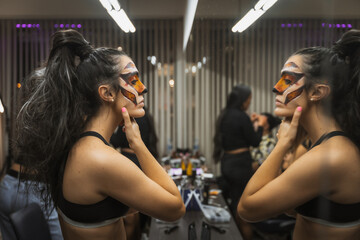 Halloween party preparations, woman looking in the mirror fixing her makeup in the beauty salon