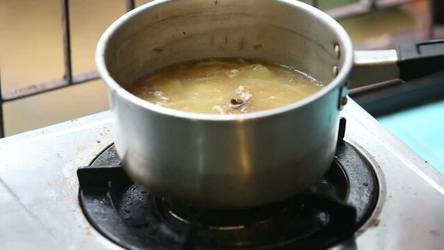 Stirred ladle chicken soup in saucepan on the gas stove turned off the gas and steam coming