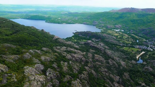 Ribadelago township in spanish countryside by sanabria lake, aerial dolly below ponytails on rocks