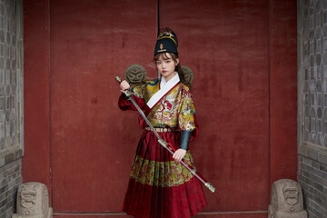 An Oriental beauty dressed in ancient warrior attire, wielding a weapon - obrazy, fototapety, plakaty