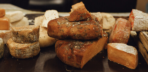 hand made baked stuffed rolls and pieces of cheese. Delicious pastries on wooden cutting board and parchment paper at the street food fair. Soft focus blurred and noise effect