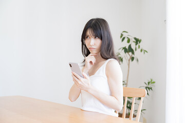 Obraz na płótnie Canvas 携帯を持ち考える日本人女性