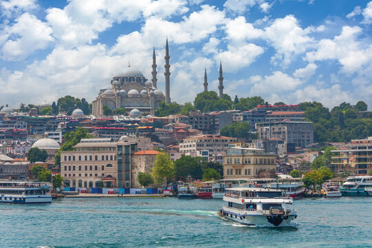 View of the central historical part of Istanbul with old buildings and a large mosque on a hill, ships and ferries with people floating in the Bosphorus.