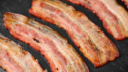 Frying bacon slices in oven. Crispy pieces of fried delicious bacon. Traditional breakfast