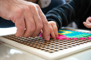 mains d'enfant et adulte sur un jeu de construction