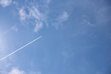 airplane flies in white clouds in a blue sky.