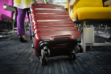Unrecognizable female tourist with suitcase walking the aisle on plane. Travel and summer vacation...