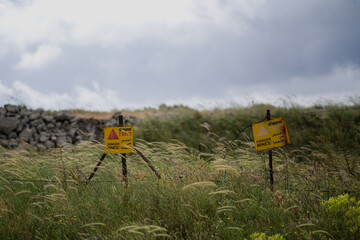 In the Golan Heights, a fence marks off an area. A bright yellow sign in Hebrew, Arabic, and...