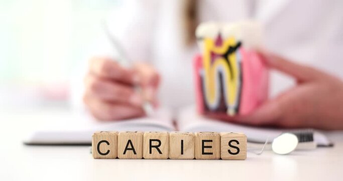Dentist fills in patient medical history and word caries. Caries is complex slowly ongoing pathological process occurs in hard tissues of the tooth