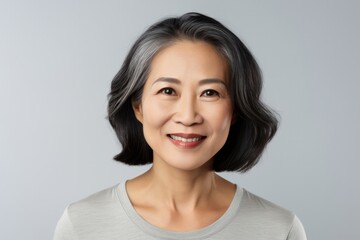 Fototapeta premium Optimistic senior japanese female looking at camera with smile on gray background. Positive emotion