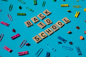 Educational greeting announcement for students and teacher. Saying BACK TO SCHOOL text on wooden blocks on creative vivid background with stationery supplies around. Concept of new school year Top