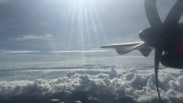 Cloudy day time sky through flying plane window sun flair  aircraft propellor