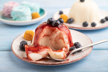 White milk jelly with blueberry jam on blue wooden,  side view, selective focus.