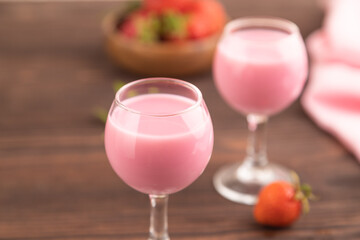 Sweet strawberry liqueur in glass on a brown wooden background. side view, selective focus