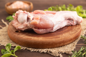 Raw turkey wing on a wooden cutting board on a brown wooden background. Side view, selective focus.