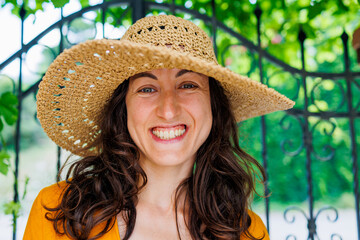 young and beautiful girl in a hat and yellow dress smiles at the camera. happy girl on vacation.