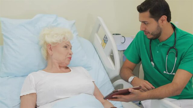 Doctor shows something on his tablet to female patient