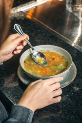 A woman in a cafe eats a low-calorie vegetable soup.