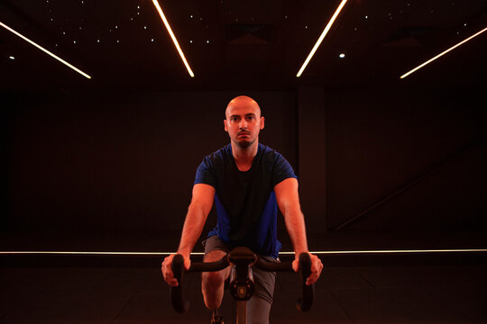 Portrait of young man with prosthetic legs riding stationary bicycle