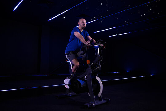 Young man with prosthetic legs riding stationary bicycle