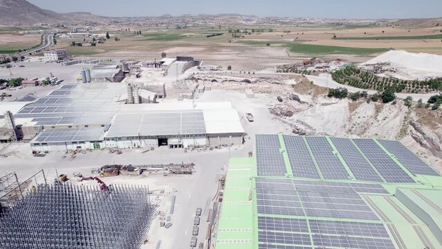 Industrial buildings of open pit limestone mine with solar photovoltaic panels mounted on the roof. Solar panels on rooftop aerial view