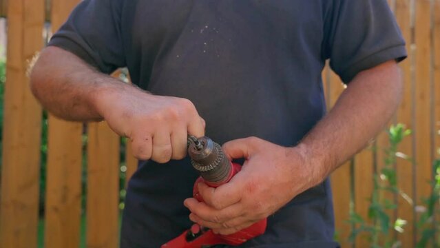 Male builder using drill to screw the screws off the timber	
