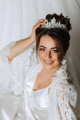 Gorgeous bride portrait in her robe wearing tiara. Beautiful bridal makeup and hairstyle and hair accessories. Bride to be smiling portrait