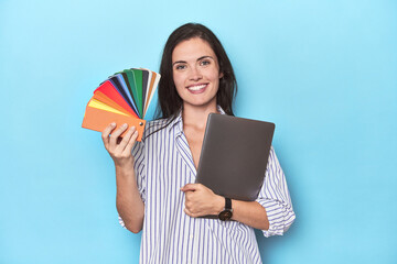 Graphic designer with laptop and color palette on blue