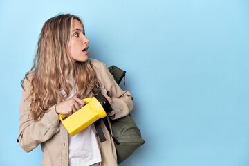 Traveler with backpack and flashlight in blue studio