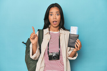 Filipina with camera, tickets, backpack on blue having some great idea, concept of creativity.