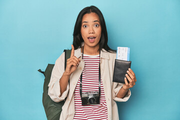 Filipina with camera, tickets, backpack on blue having an idea, inspiration concept.
