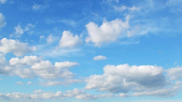 White cumulus clouds float slowly in the blue sky. A dreamy background with clouds smoothly changing their shape.