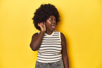 Fototapeta na wymiar African-American woman with afro, studio yellow background trying to listening a gossip.
