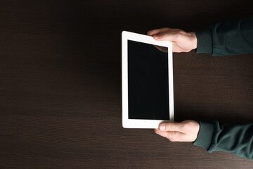 Man working with tablet at wooden table, top view. Space for text
