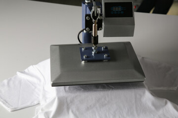 Printing logo. Heat press with t-shirt on white table