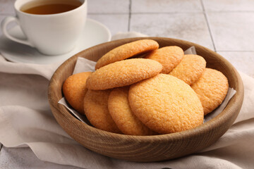 Delicious Danish butter cookies and tea on white tiled table, closeup