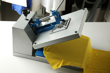 Printing logo. Heat press with yellow t-shirt on white table