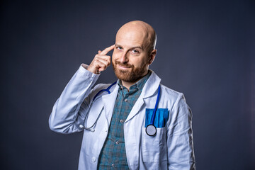 Photo of doctor with beard and stethoscope posing thinking with blue background and medical white coat