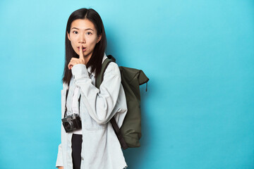 Young Asian traveler ready to capture adventures, keeping a secret or asking for silence.
