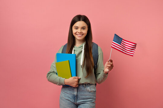 Happy teen exchange student girl with notebooks holding usa american flag