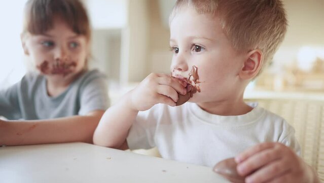 children eat chocolate. dirty little baby kids in the kitchen eating chocolate in the morning. happy family eating lifestyle sweets kid dream concept. baby dirty face eating chocolate cocoa